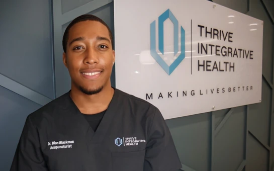 Acupuncturist Dion Blackmon standing in front of a Thrive Integrative Health sign