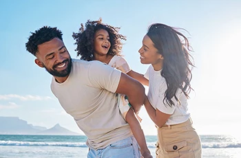 A happy family of three walking together on a beach
