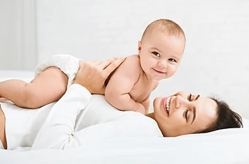 A mother lying with her baby on her chest, smiling