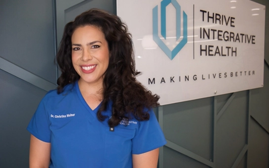 Chiropractor Christina Wellner standing beside a Thrive Integrative Health sign
