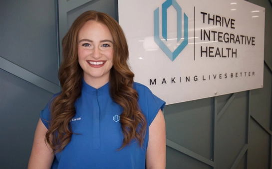 Chiropractor Kate Reiter standing beside a Thrive Integrative Health clinic sign